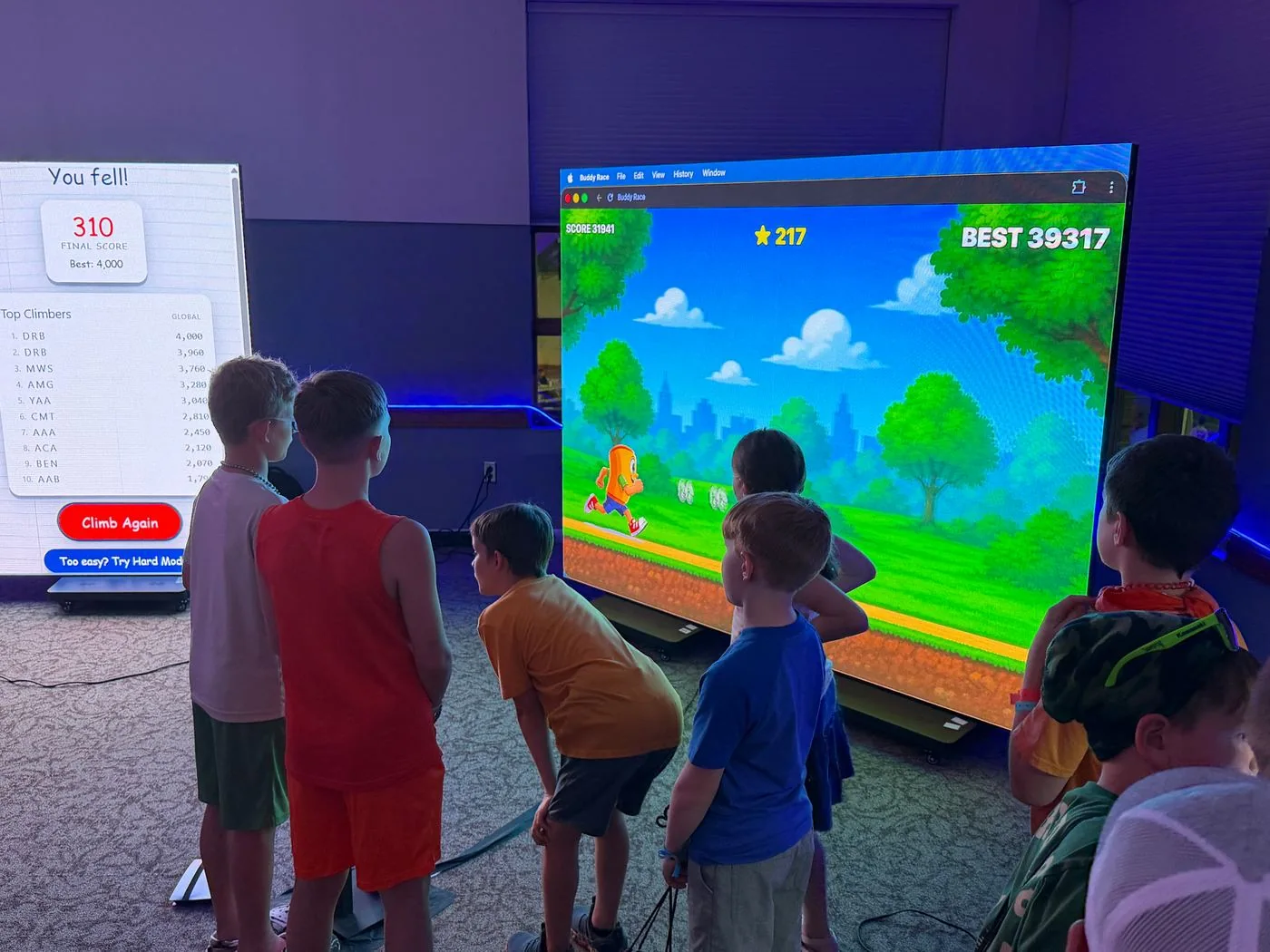 Children gather around a large screen to play Buddy Race.